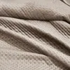 A close-up view of a beige quilted blanket. Podgląd zdjęcia produktu