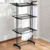 A black metal drying rack with clothes hanging on it, placed indoors on a wooden floor near a window and a patterned wall. Produktbild-Vorschau