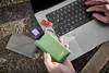 A person's hands are holding a green power bank next to a laptop, with a USB drive and an SD card visible. Voir les images du produit