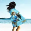A person on a beach wearing a blanket with a Legend of Zelda print. Anteprima dell’immagine prodotto