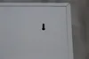 A close-up view of the back of a gray metal cabinet, showing a keyhole-shaped mounting bracket. Produktbild-Vorschau