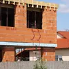 Construction site with a building under construction and a neighboring house. Voir les images du produit