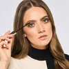 A woman applying mascara to her eyelashes. Podgląd zdjęcia produktu