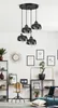 A modern living room with a multi-pendant light fixture, shelves with decor, and a desk with a clock. Produktbild-Vorschau