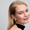 A close-up portrait of a woman wearing earrings. Voir les images du produit