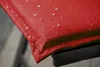 Close-up of a red fabric with water droplets on it, resting on a black metal frame. Produktbild-Vorschau
