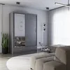 A modern bedroom or living room setting featuring a gray sliding door wardrobe with a mirrored panel, a sofa, a coffee table, and a floor lamp. Voir les images du produit