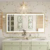 A well-lit bathroom vanity with a large LED mirror, double sinks, and decorative elements. Náhled obrázku produktu