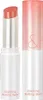 Two lip balms are shown side-by-side against a white background. The left balm is open, showing the coral-colored product. The right balm is closed, with a gradient pink cap. Náhľad obrázku produktu