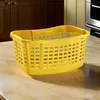 A yellow laundry basket sits on a countertop. Voir les images du produit