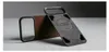 A brown leather iPhone case and a black MagSafe accessory are displayed on a gray surface against a dark gray background. Produktbild-Vorschau