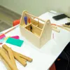 A wooden toolbox kit for children, with tools inside, on a white table with other craft supplies. Produktbild-Vorschau