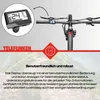 A close-up of an e-bike display and handlebars, with a background image of a mountain landscape. Produktbild-Vorschau