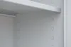 A close-up interior view of a gray metal storage cabinet shelf and its support pins. Produktbild-Vorschau