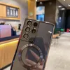 A close-up shot of a phone case with a camera protection and MagSafe ring, set against a blurred background of a cafe or store. Náhled obrázku produktu