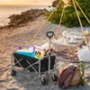 A beach picnic scene with a folding wagon filled with picnic items, a table set for a meal under a tent. Produktbild-Vorschau