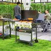 Two men are grilling outdoors in a patio area with lush green grass and a greenhouse-like structure in the background. Náhled obrázku produktu