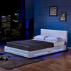 A modern white bed with blue LED lighting, set against a dark blue wall with framed artwork and a cityscape view through a window. Náhled obrázku produktu