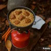 A camping stove with a pot of food cooking on it, set in an outdoor, natural environment. Náhled obrázku produktu