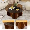 A round coffee table with a glass top and wooden base, shown in a living room setting with a sofa and rug. The image is a collage with close-up views highlighting features. Produktbild-Vorschau