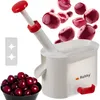 A cherry pitter with a bowl of cherries and loose cherries in the background. Produktbild-Vorschau