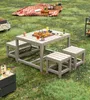 A picnic set with a table and benches on a grassy lawn, with a picnic blanket and basket in the background. Anteprima dell’immagine prodotto