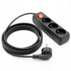 A black power strip with three outlets and a red illuminated switch, connected to a coiled black power cord and a black plug. The product is shown on a white background. Podgląd zdjęcia produktu