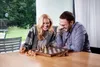 A couple playing chess in a modern living room with a view of a garden. Podgląd zdjęcia produktu