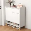 A white shoe cabinet with wooden legs, decorated with a vase of flowers, books, and a handbag on top. Náhľad obrázku produktu