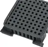 A close-up, angled view of a dark gray, square plastic filter with a grid pattern on top and slotted sides. Produktbild-Vorschau