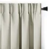 A close-up view of cream-colored blackout curtains hanging from a black curtain rod. Podgląd zdjęcia produktu