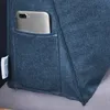 A close-up view of a dark blue fabric product, likely a cushion or pillow, with a smartphone placed in a pocket on its side. A small white label is also visible. Produktbild-Vorschau