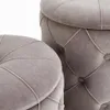 A close-up view of two grey tufted ottomans. Produktbild-Vorschau