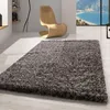 A shaggy rug in a modern living room with a stylish wooden chair and a large window overlooking the ocean. Podgląd zdjęcia produktu