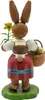 Zu sehen ist eine Hasenfigur in traditioneller Kleidung die einen Korb mit Eiern trägt und eine Blume in der Hand hält während sie auf einem grünen Sockel steht Produktbild-Vorschau