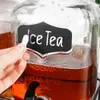 A hand is writing 'Ice Tea' on a chalkboard label attached to a glass beverage dispenser filled with iced tea. Náhľad obrázku produktu