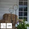 Two decorative sphere lights with LEDs are placed in front of hay bales and flowers, next to a house. Produktbild-Vorschau
