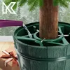 A Christmas tree stand is being watered, with a gift box in the foreground. Voir les images du produit