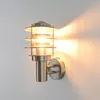A modern outdoor wall light made of stainless steel and glass, mounted on a white wall. Produktbild-Vorschau