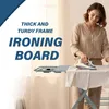 A woman is ironing clothes on an ironing board in a well-lit room. Produktbild-Vorschau