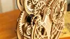 A close-up view of a wooden mechanical owl model with intricate gears and mechanisms. Produktbild-Vorschau