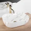 A close-up shot of a marble-patterned sink with a gold faucet, set against a white background and a wooden countertop. Anteprima dell’immagine prodotto