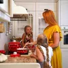 A mother and her two daughters are in a kitchen, cooking together. Anteprima dell’immagine prodotto