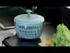 A salad spinner is shown on a kitchen counter next to lettuce and tomatoes. Produktbild-Vorschau