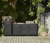 An outdoor kitchen setup with a gas pizza oven and cabinets on a wooden deck, surrounded by greenery. Produktbild-Vorschau