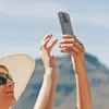 A person taking a selfie outdoors with a smartphone in a clear case. Podgląd zdjęcia produktu
