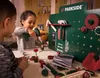 Two children playing with a toy workbench and tools in a room. Produktbild-Vorschau