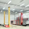 A clean and well-lit automotive workshop with a car lift, tool chests, and a tire. Produktbild-Vorschau