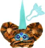 A close-up studio shot of a toy Furby Furblet with tiger stripes, a turquoise horn, and blue eyes, along with a light blue accessory. Podgląd zdjęcia produktu