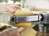 Hands using a Kenwood pasta maker attachment to roll out dough. Produktbild-Vorschau